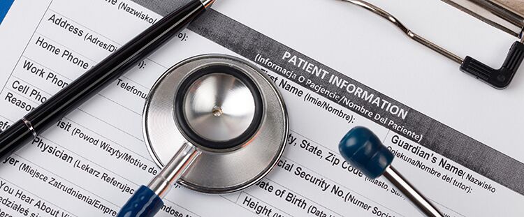Stethoscope and pen laying on patient information blank